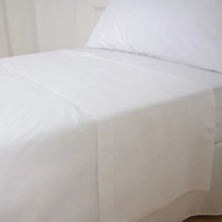 Drap blanc 144 fils plié sur un lit d'hôtel